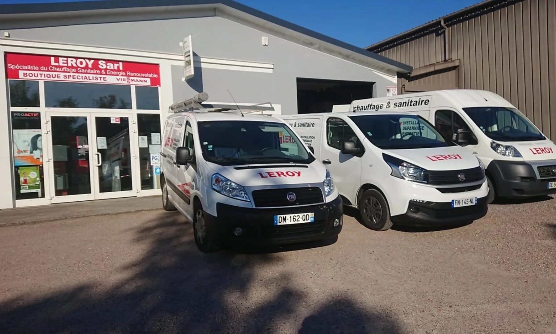 Le magasin Leroy et trois camionnettes blanches de l'entreprise devant la vitrine